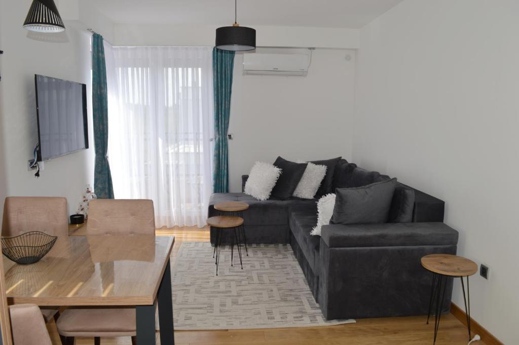 a living room with a black couch and a table at Apartman Ras in Vrnjačka Banja