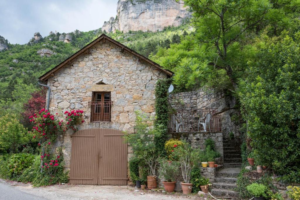 - un petit bâtiment en pierre avec une porte et des fleurs dans l'établissement Gîte La Grange, Gîtes de France 2/4 personnes à la Caze, à Saint-Pierre-des-Tripiers
