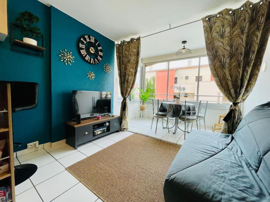 un salon avec un canapé et une horloge au mur dans l'établissement Cap Studio Parking Wifi Port Plage, au Cap d'Agde