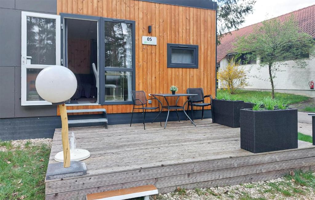 a house with a wooden deck with a table and chairs at Tiny Haus 05 Am Brombachsee in Pleinfeld