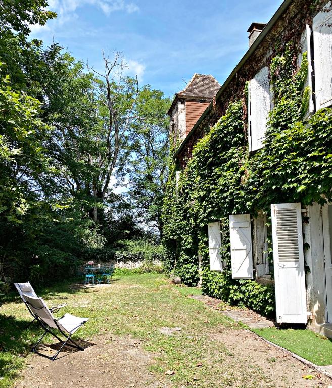 une chaise assise à côté d'un bâtiment couvert de lierre dans l'établissement Chez Malou, à Pinsac