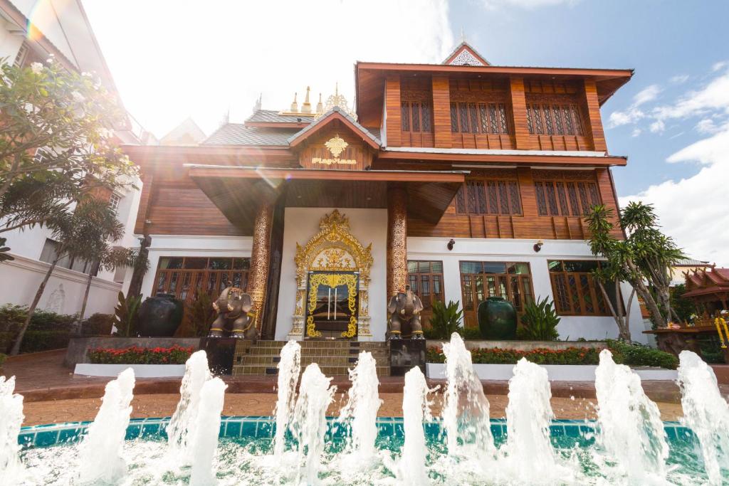 uma casa com uma fonte em frente em Pingviman Hotel em Chiang Mai