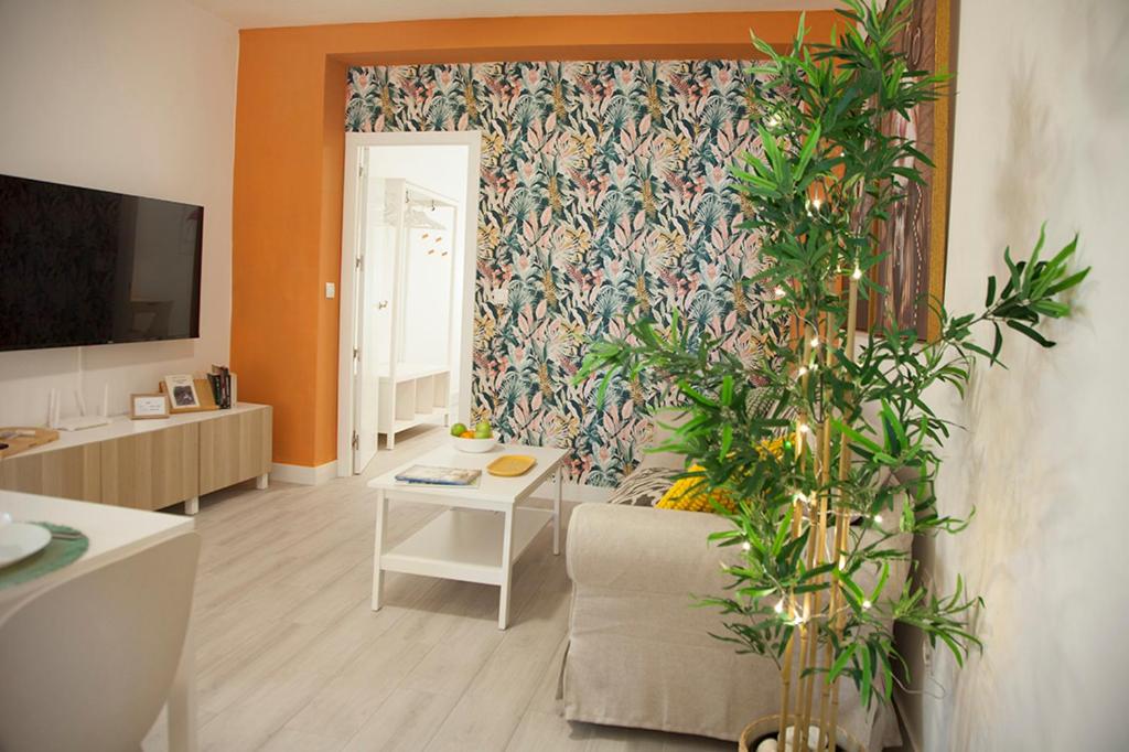 un salon avec un canapé et une plante dans l'établissement Sanlúcarsun Apartamento en el centro, à Sanlúcar de Barrameda