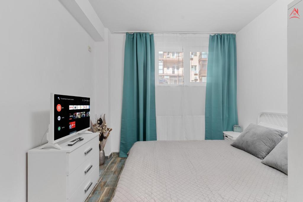a white bedroom with green curtains and a bed at Petite Blue Apartment in Roşu