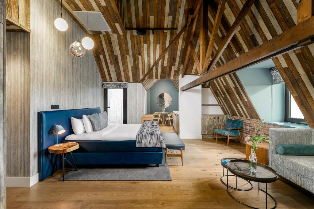 een slaapkamer met een blauw bed en een bank bij Cityhotel Wood in Middelburg