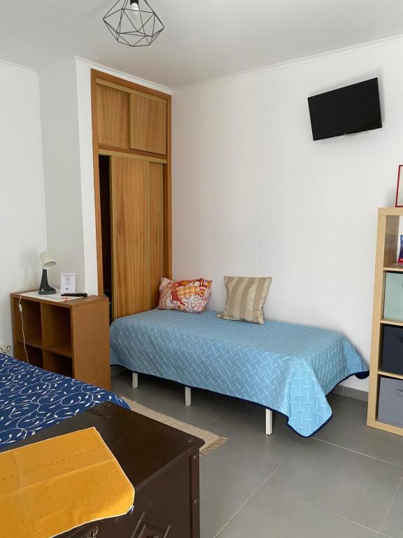 a bedroom with two beds and a tv on the wall at Casa Praia do Sul in Ericeira
