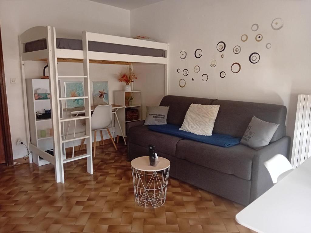 - un salon avec un canapé et des lits superposés dans l'établissement Les pinèdes, à Sète
