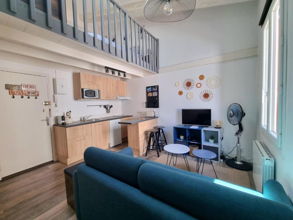 un salon avec un canapé bleu et une cuisine dans l'établissement Joli studio en plein centre historique, à Aix-en-Provence
