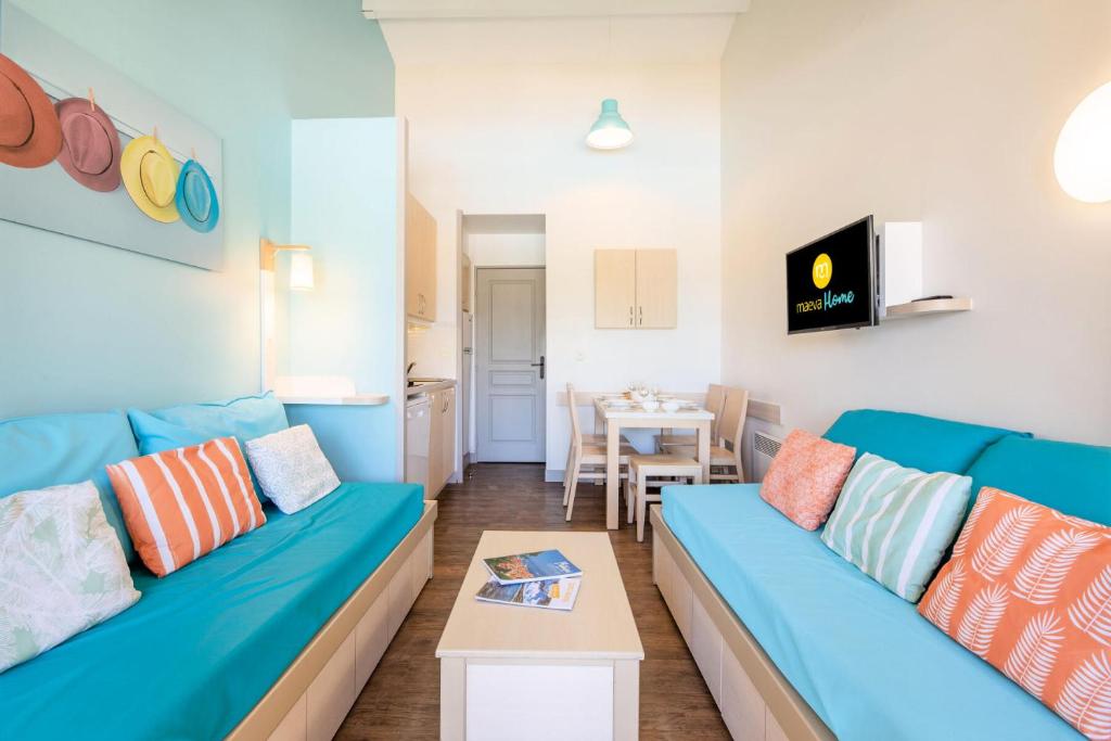 un salon avec un canapé bleu et une table dans l'établissement Résidence Les Parcs de Grimaud - maeva Home - Studio 4 personnes - Sélection MAE-4361, à Grimaud