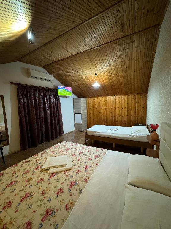 a bedroom with a large bed with a wooden ceiling at Holiday Guest-House in Përmet