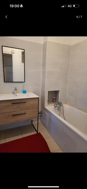 une salle de bain avec une baignoire, un lavabo et un miroir dans l'établissement T3 bien équipé, à Marseille