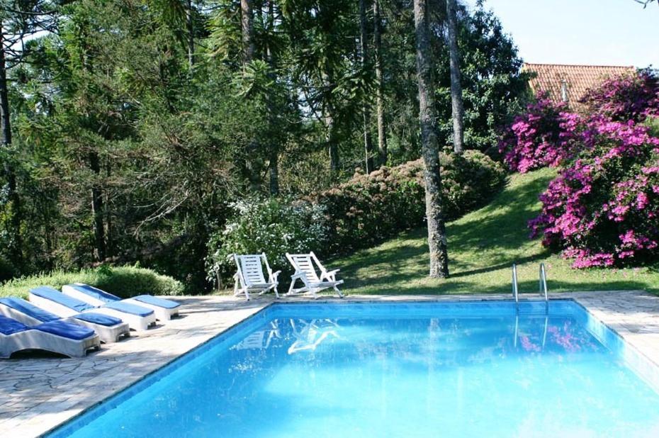 uma piscina com 2 espreguiçadeiras e ahaps em Pousada Passaredo em Gonçalves