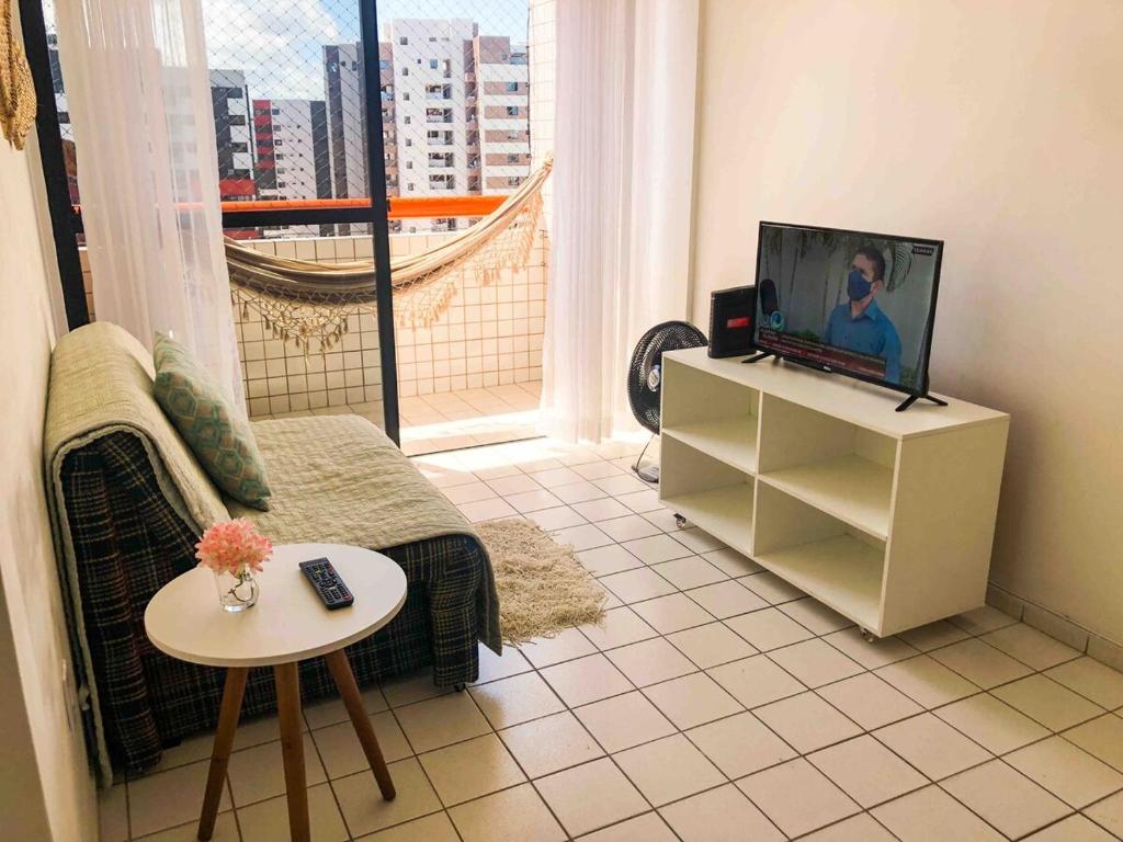ein Wohnzimmer mit Fernseher und Tisch in der Unterkunft RF-86: Apê completo e aconchegante na Ponta Verde in Maceió
