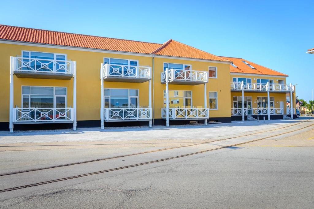 un bâtiment jaune avec des balcons blancs dans une rue dans l'établissement Skagen Havn Lejligheder, à Skagen