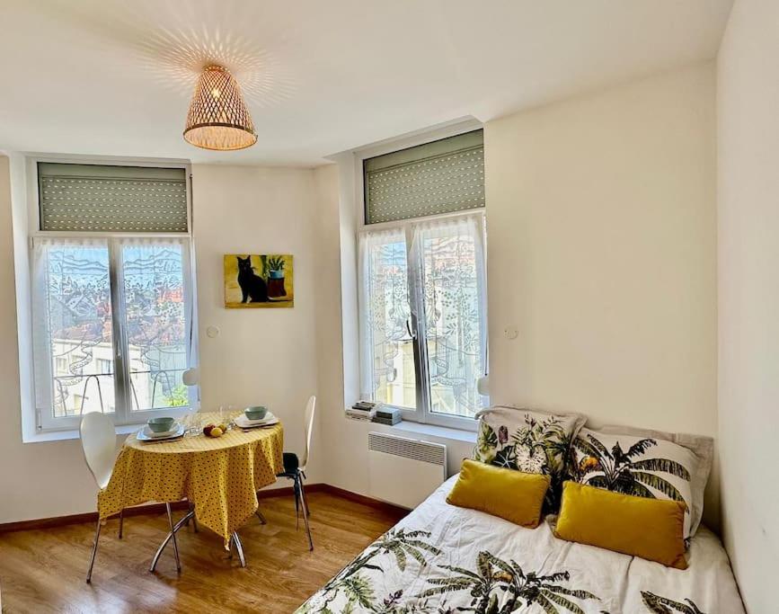 une chambre avec un lit, une table et des fenêtres dans l'établissement La Capucine, à Berck-sur-Mer