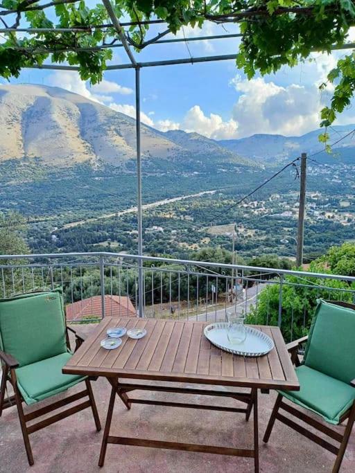a wooden table and chairs on a balcony with a view at Kefalonia Alexis house in Pilaroú