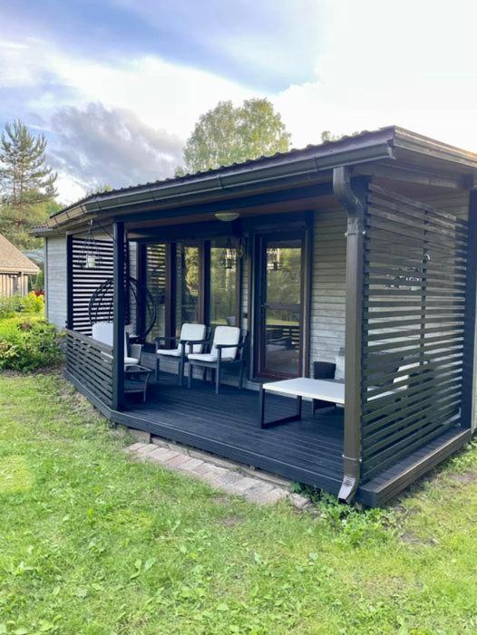 Un cenador con sillas y un banco en una terraza. en Sea Side house (50m2) Lejas Ziediņi, en Plieņciems