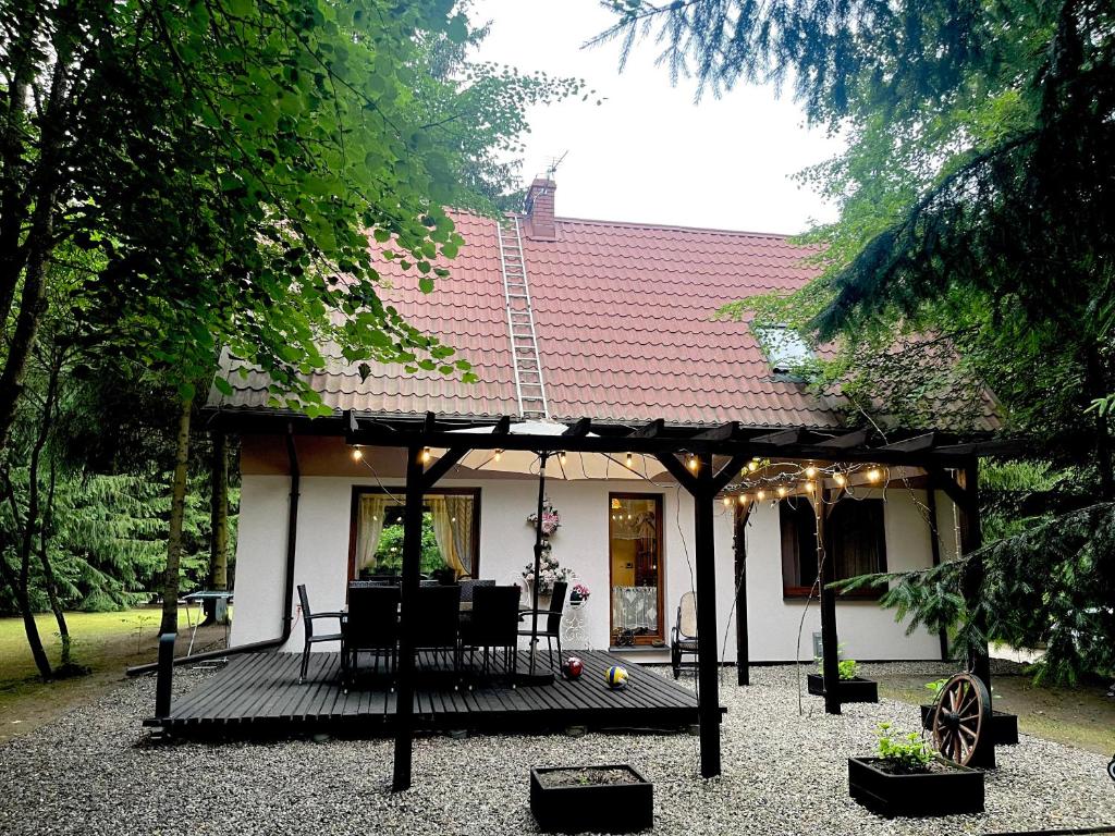a house with a deck with a table and chairs at Sielanka Kretowiny in Kretowiny