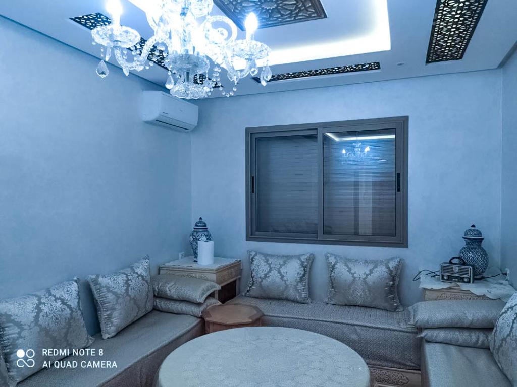 a living room with a couch and a chandelier at Appartement à Bouznika prêt du plage Dahomey, plage bouznika, Bahia beach in Bouznika