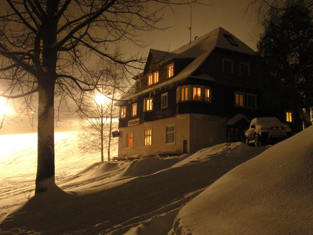 une maison dans la neige la nuit dans l'établissement Pomněnka, à Pec pod Sněžkou