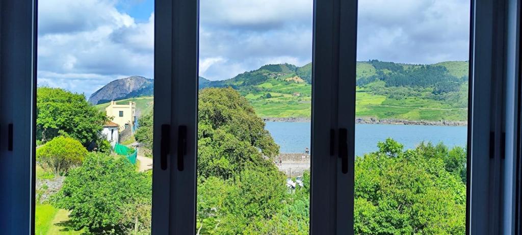 a window with a view of a lake and mountains at Rincón del Mar, Mundaka in Mundaka
