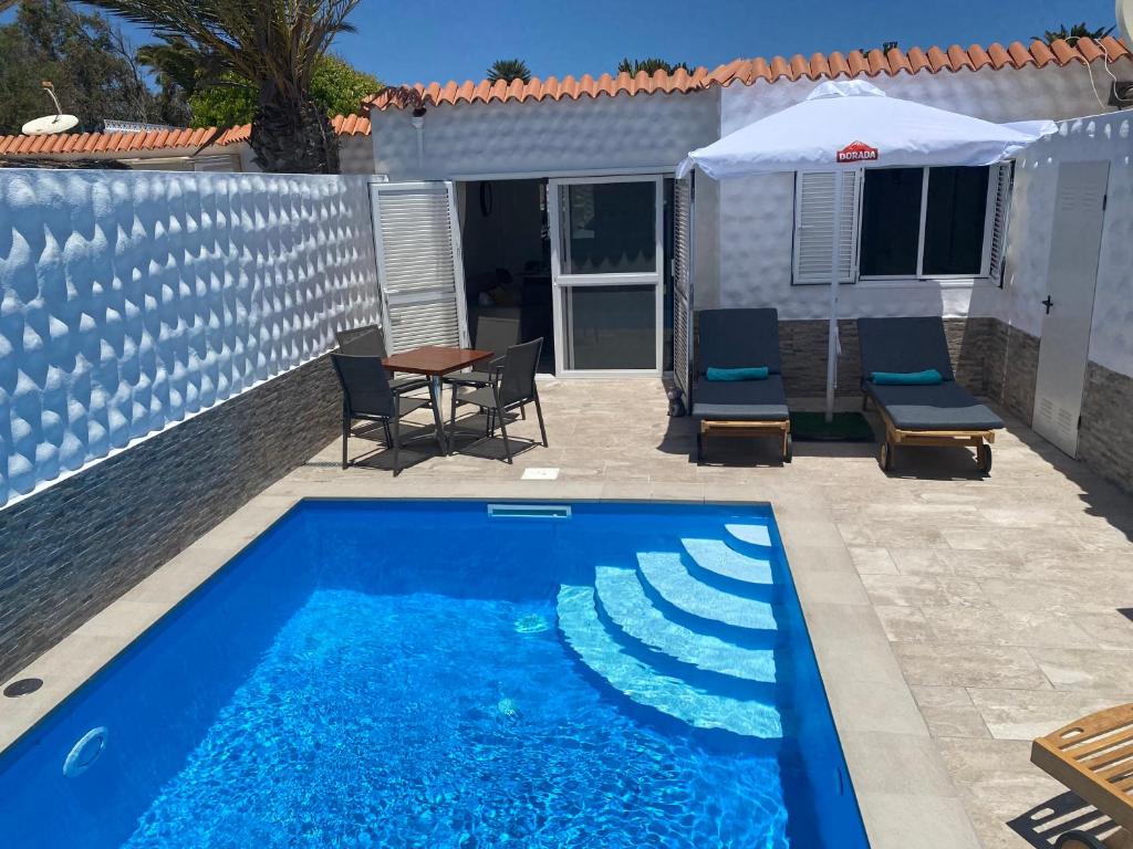 a blue swimming pool with chairs and a table at Casa Dos Jotas in Costa Calma