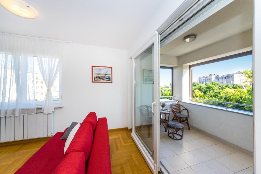 a living room with a red couch and a large window at Apartman Diana in Zadar