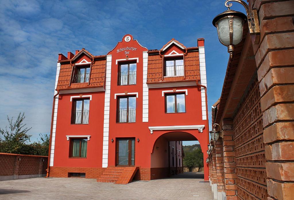 ein rotes Gebäude mit einem Torbogen davor in der Unterkunft Schassburger Tor in Sighişoara