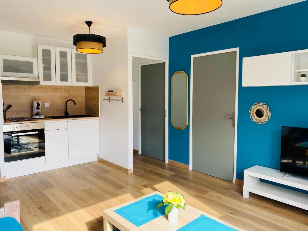 un salon avec un mur d'accent bleu dans l'établissement Bel appartement dans résidence de standing avec piscine et tennis, à Saint-Cyprien