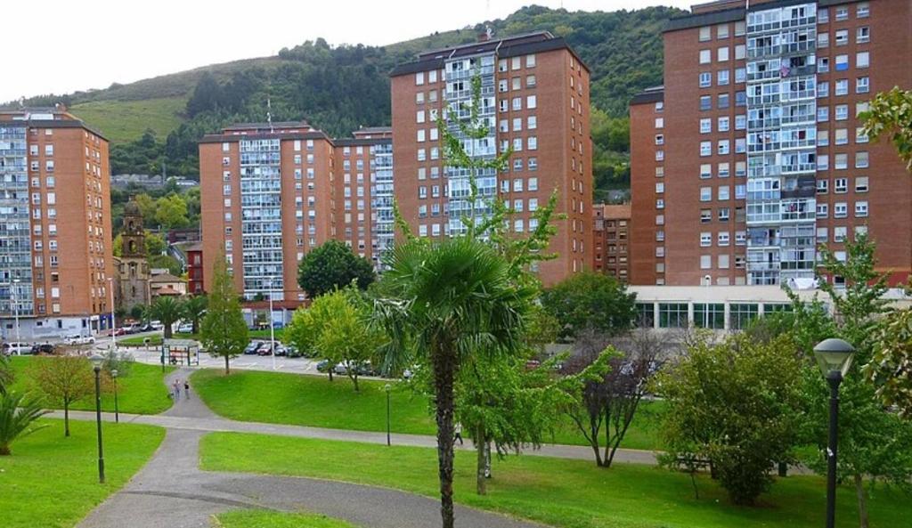 una città con edifici alti e un parco con palme di Habitación 1 con vistas a Bilbao