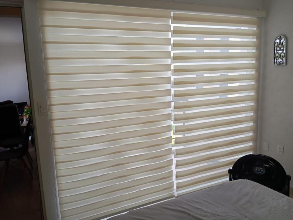 ein Schlafzimmer mit einem Fenster mit Jalousien in der Unterkunft Departamento con alberca in Tecolote