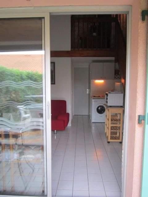 un salon avec un canapé rouge et une cuisine dans l'établissement Villa de vacances avec terrasse aux Capellans, à Saint-Cyprien