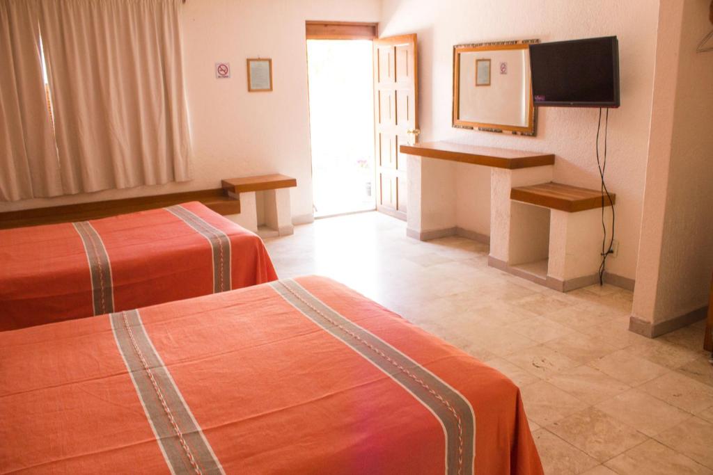 a hotel room with two beds and a television at Hotel Avenida Ixmiquilpan in Ixmiquilpan