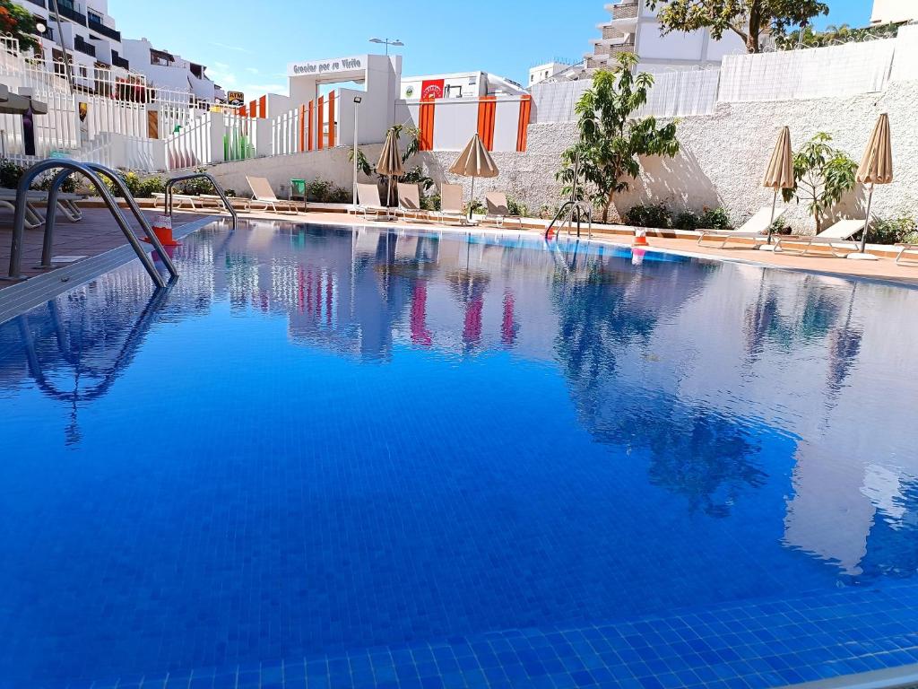 een groot blauw zwembad met parasols bij HOME LOS ELEFANTES in Playa del Inglés