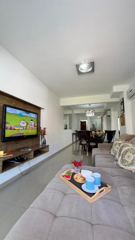 a living room with a couch and a tv at Apto Lírio da Paz- 3 Quartos com sacadas,espaçoso e de frente para avenida principal! in Piratuba