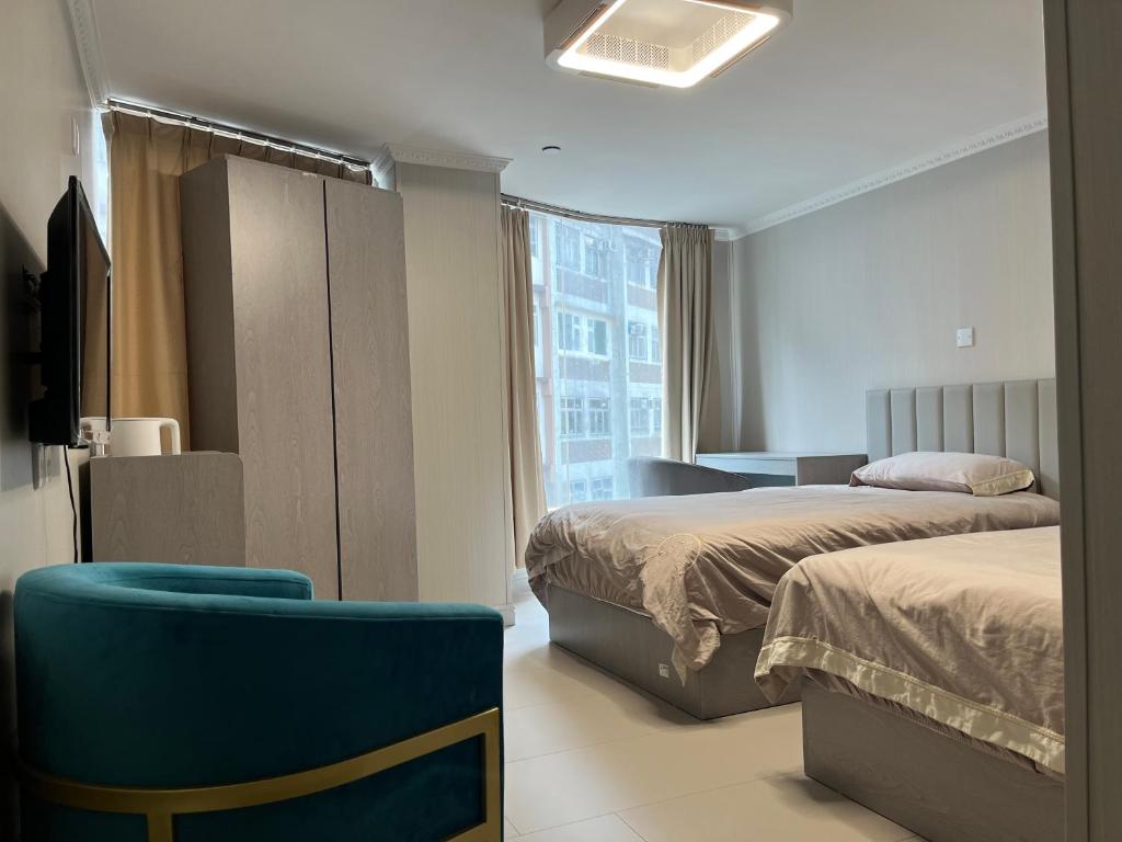 Pokój hotelowy z 2 łóżkami i niebieskim krzesłem w obiekcie 皇后超級管家 w Hongkongu
