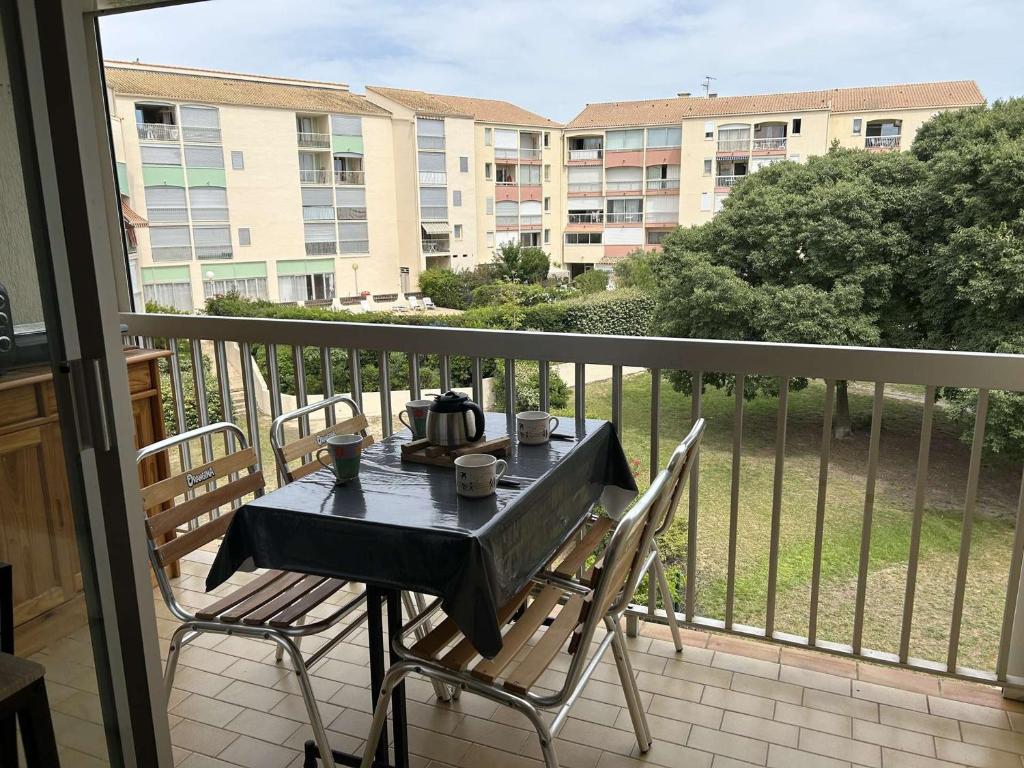 une table et des chaises sur un balcon avec vue sur un immeuble dans l'établissement Studio Cabine 4 couchages, proche Seaquarium, plage et commerces, avec terrasse et barbecue, Le Grau-du-Roi - FR-1-250-289, au Grau-du-Roi