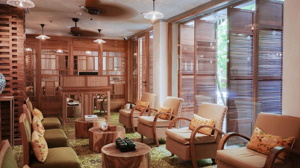 a living room with chairs and a piano in a room at Amnaya Resort Nusa Dua in Nusa Dua