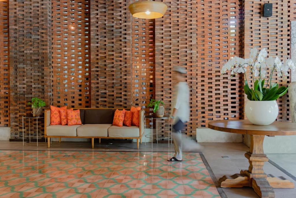a person walking through a lobby with a couch and a table at Amnaya Resort Nusa Dua in Nusa Dua