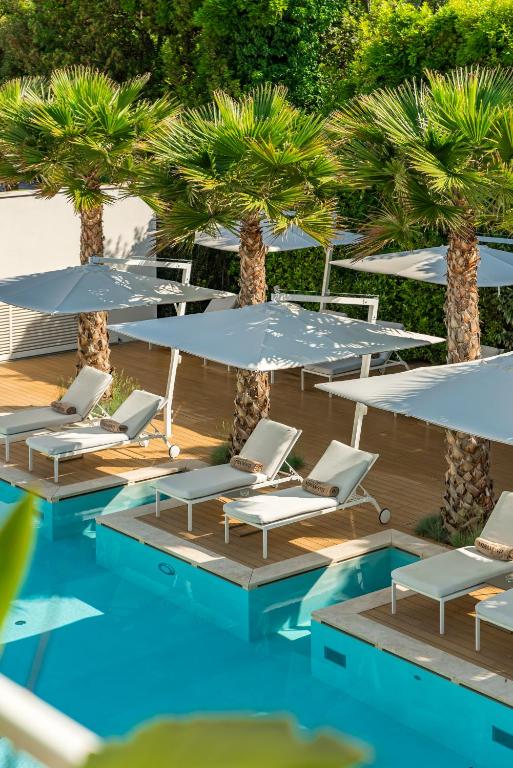 a group of chairs and umbrellas next to a pool at Resort Miramonti in Forte dei Marmi
