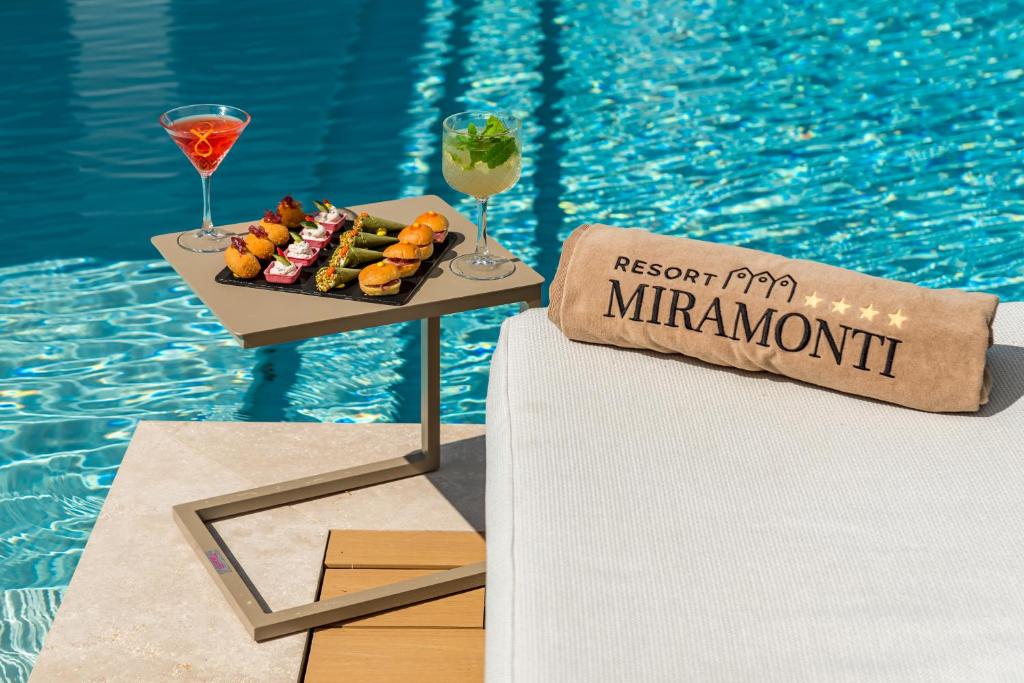 a table with a tray of food next to a swimming pool at Resort Miramonti in Forte dei Marmi