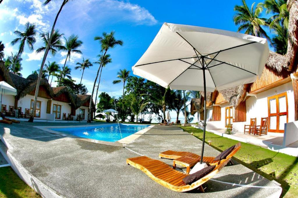 a pool with two lounge chairs and an umbrella at Elysia Beach Resort in Donsol