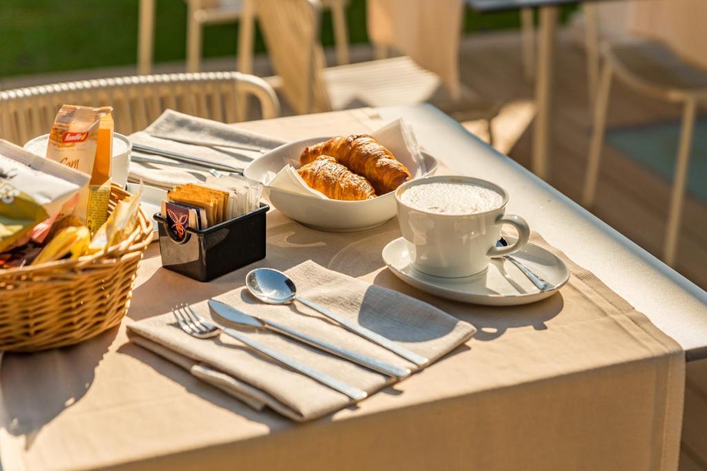 a table with a cup of coffee and a basket of pastries at Resort Miramonti in Forte dei Marmi
