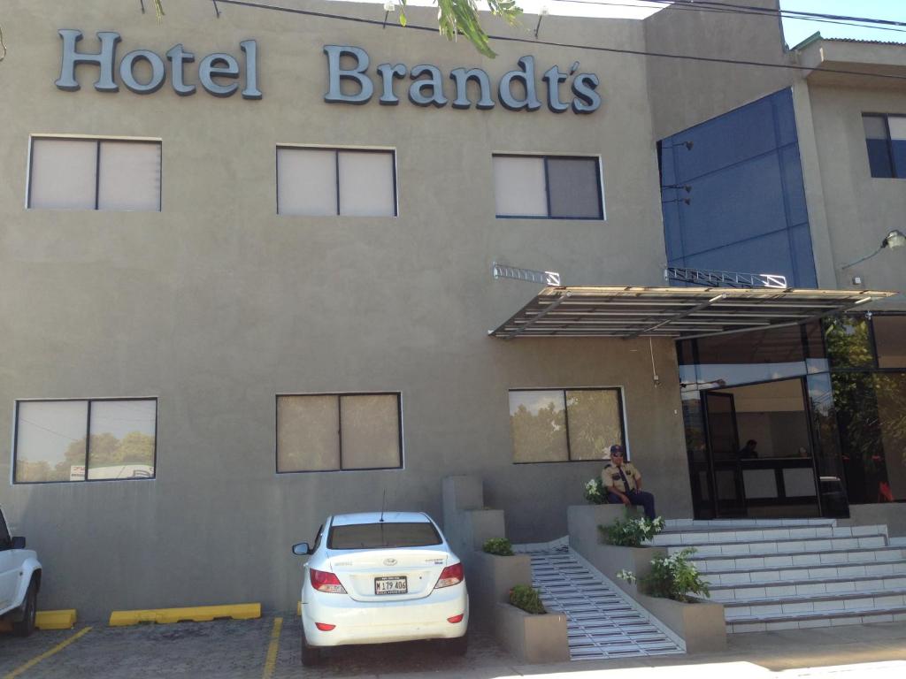 a white car parked in front of a hotel brands building at Hotel Brandts Ejecutivo Los Robles in Managua