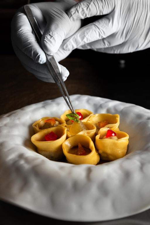 a person holding a knife in a plate of food at Resort Miramonti in Forte dei Marmi