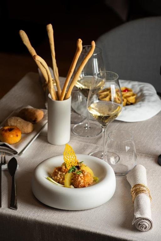 a table with a plate of food and glasses of wine at Resort Miramonti in Forte dei Marmi
