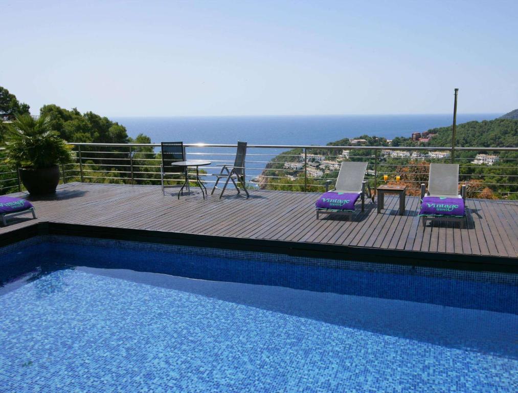 a swimming pool with chairs and a table and the ocean at Mar Bona in Tamariu