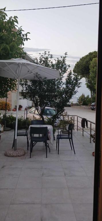 a patio with benches and an umbrella and a table at Tsampikas House in Faliraki