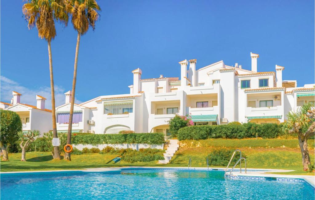 a large white building with a swimming pool and palm trees at Residencial Torrenueva in La Cala de Mijas