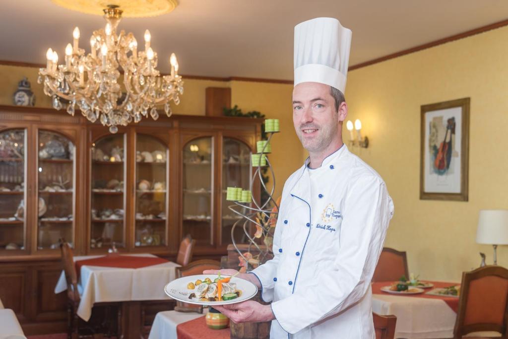 um chef a segurar um prato de comida num restaurante em Hostellerie Val Fleuri em Mersch